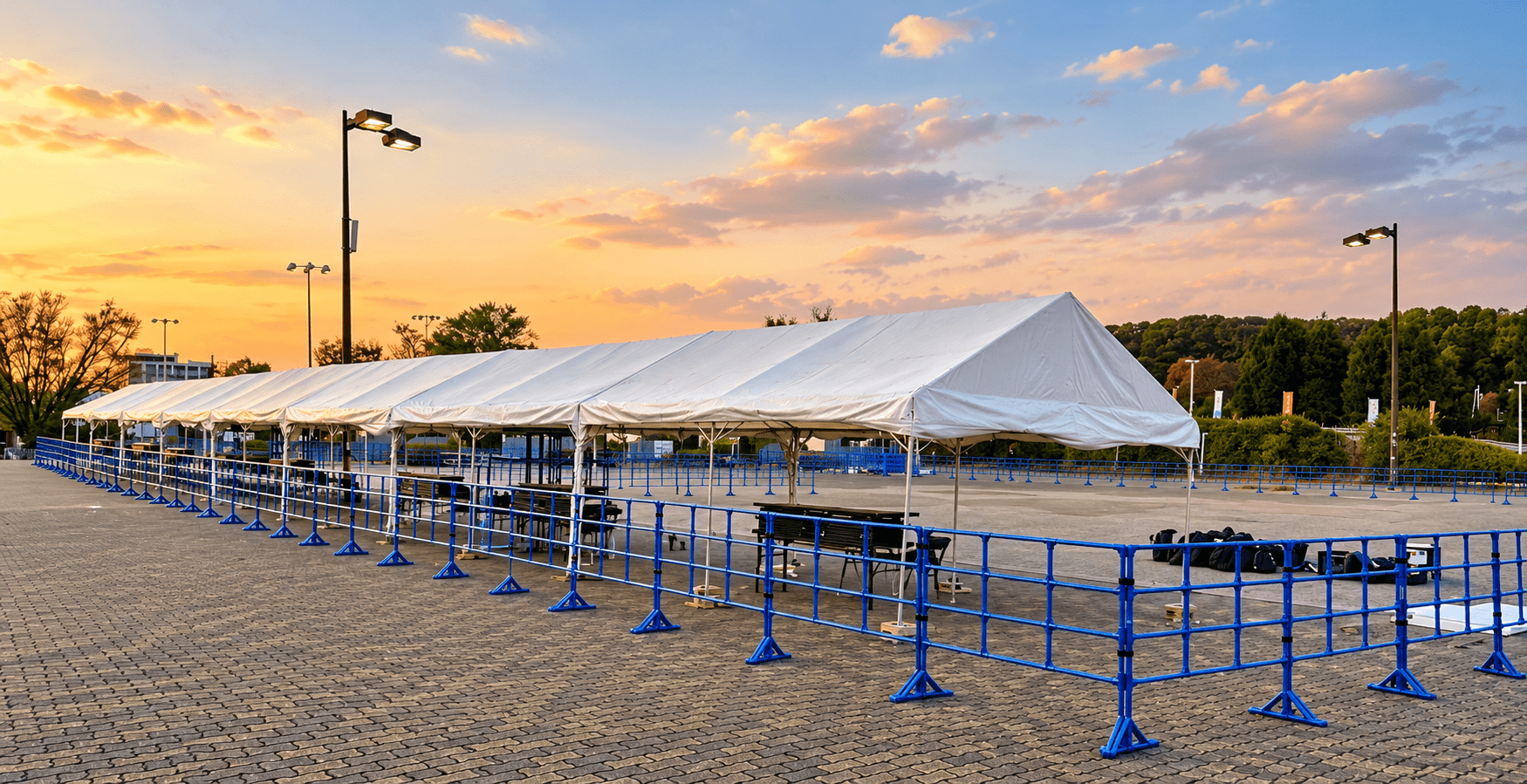 Blue event fences arranged beside a white event tent at an outdoor venue