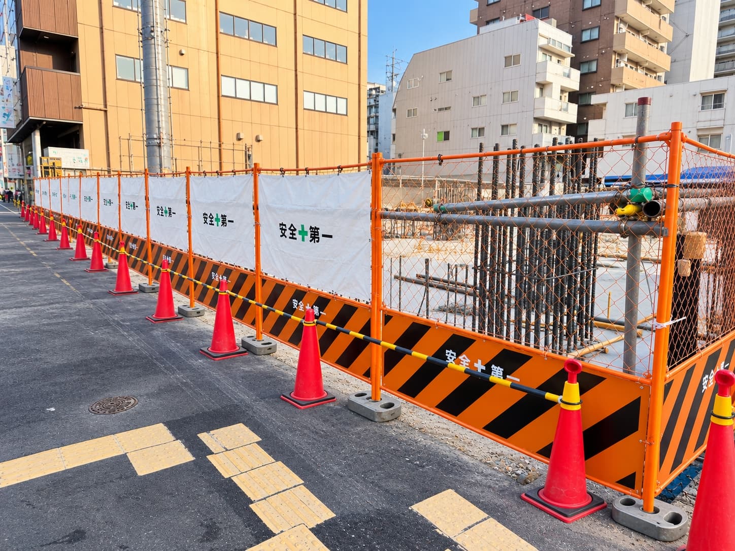 Orange mesh site fence with cast iron base weights at an active construction site